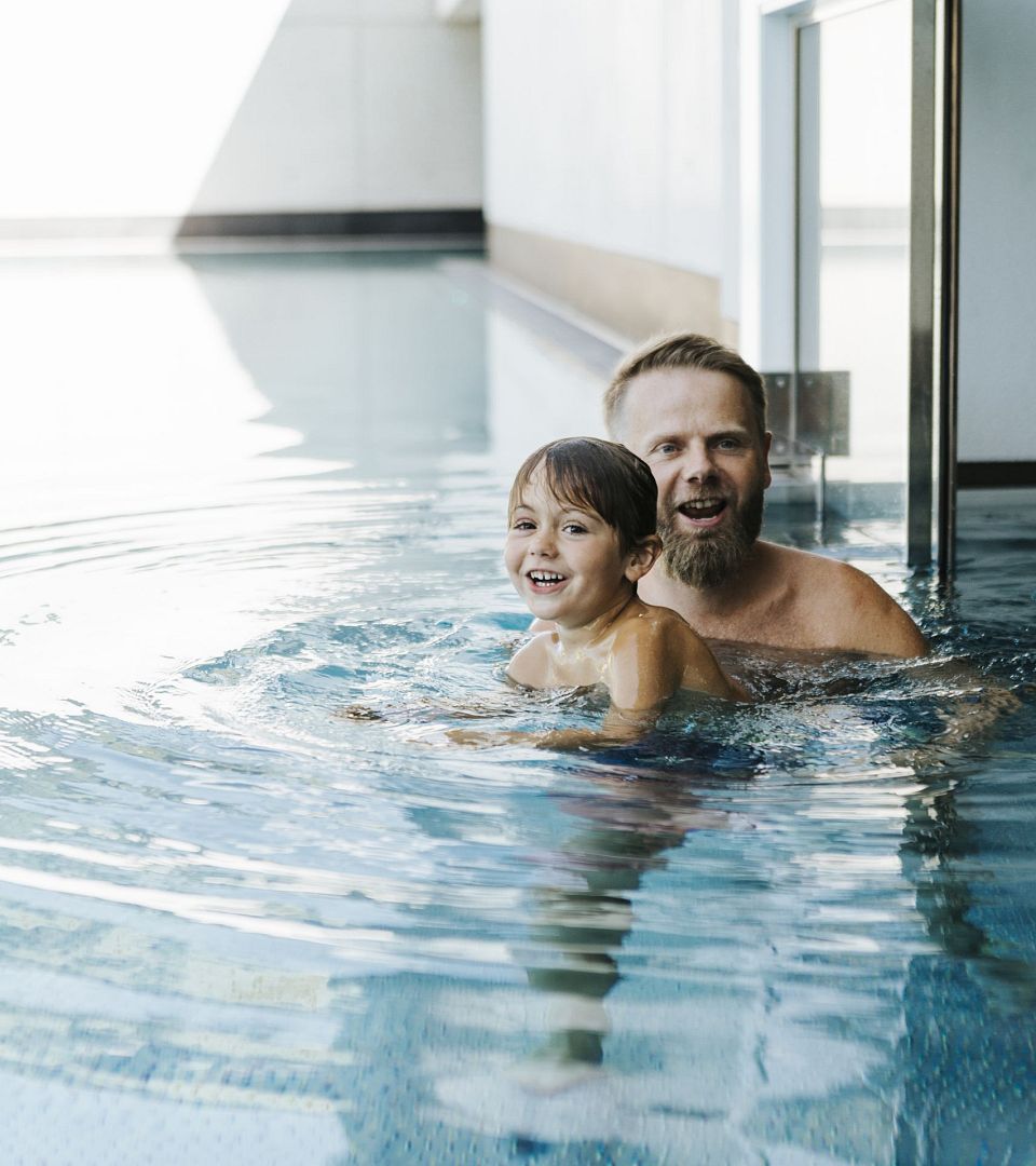 Vater und Kind schwimmen gemeinsam im Innenpool des Thurnerhof.